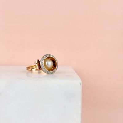 gros plan d'une bague en or avec une perle et des diamants