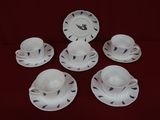 six tasses et soucoupes sont posées sur une nappe rouge