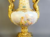 a gold vase with a painting of cherensils on it