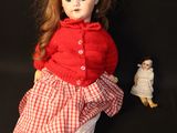 a doll that is sitting next to a doll on a black background