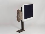 a rock that is sitting on a stand next to a screen