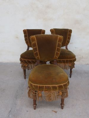 three chairs and a foot stool are sitting in front of a white wall
