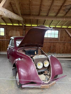 une vieille voiture, le capot ouvert, dans un garage
