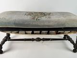 an antique foot stool with a blue and white upholstered seat