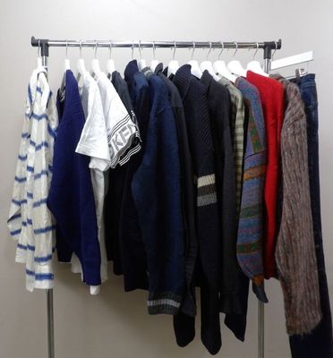 many sweaters hanging on a rack in a room