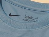 the back of a blue shirt with a black nike logo on it
