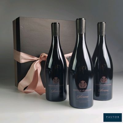 three bottles of red wine in a gift box with a pink ribbon