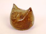 a brown cat figurine sitting on a white surface