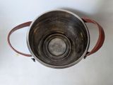 a metal bowl with a handle on a white table