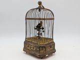 un petit oiseau dans une cage posée sur une surface blanche