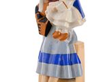 figurine représentant une femme tenant un bébé dans ses bras et un homme coiffé d'une toque de chef