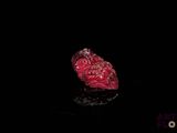 une image représentant un morceau de verre rouge posé sur une surface noire