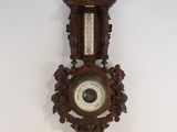 une horloge accrochée au mur, sur laquelle se trouve un baromètre