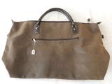 un sac à main en cuir marron, orné d'une étiquette, posé sur une surface blanche