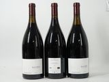 trois bouteilles de vin rouge sont posées sur une surface blanche