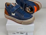 des baskets en cuir bleu à semelles orange, posées sur une boîte blanche