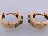 a pair of gold hoop earrings with emerald stones