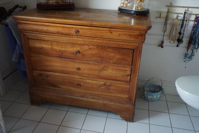 une commode en bois dans une salle de bains, avec un miroir au-dessus