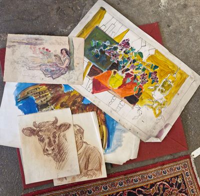 un tas d'œuvres d'art posé par terre à côté d'un tapis