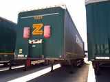 two green semi trailers that are parked next to each other