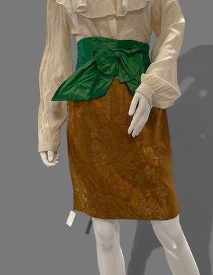 a white mannequin wearing a brown and green dress with a green belt