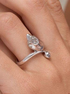 la main d'une femme tenant une bague en argent ornée d'une fleur