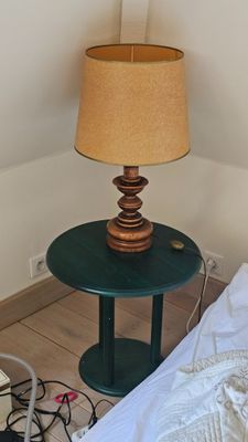 une petite table sur laquelle est posée une lampe, à côté d'un lit