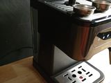 a coffee maker sitting on a wooden table next to a knife and fork