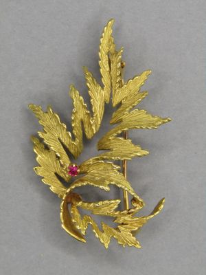une image représentant une broche en or ornée de feuilles et d'un rubis