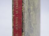 an old book sitting on top of a wooden table next to a white wall