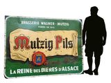 a man standing in front of a sign that says mutzen pils