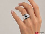 the woman ' s hand is holding a diamond and black and white ring