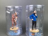two figurines of a man in a blue shirt and a man in a brown suit in a glass jar