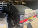 a black car parked in a garage next to a pile of boxes