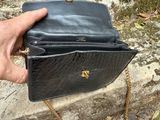 a person holding a black purse with a chain around it
