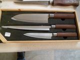 quatre couteaux dans une boîte en bois posée sur une table