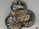 a silver plate with a flower on it next to silver spoons