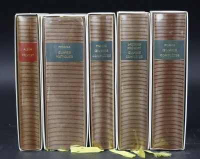 three old books are lined up on a black surface