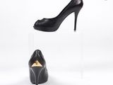 des chaussures à talons hauts noires posées sur un socle en acrylique transparent