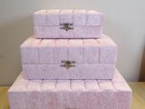 three pink boxes stacked on top of each other on a table