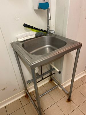 un lavabo dans un coin de la salle de bains, avec une brosse à dents posée sur le plan de travail