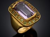 a close up of a gold ring with an amethorate and green sapphires