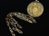 a close up of a gold coin and chain on a black background