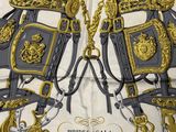 two horse bridles with gold and black details on them on a white and gray blanket