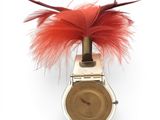 a watch with a red feather on it on a white surface