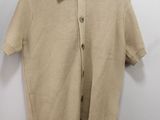 a beige sweater hanging on a hanger on a wall