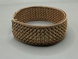 gros plan d'un bracelet en or sur une surface blanche