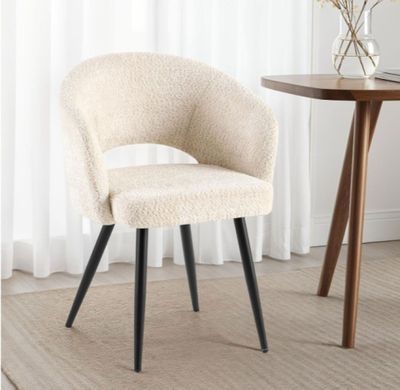 une chaise blanche aux pieds noirs et une table sur laquelle se trouve un vase de fleurs