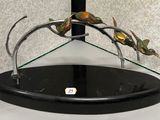 une sculpture métallique représentant un oiseau, posée sur un socle en verre