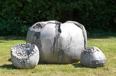 une sculpture représentant un éléphant assis dans l'herbe, près de quelques rochers